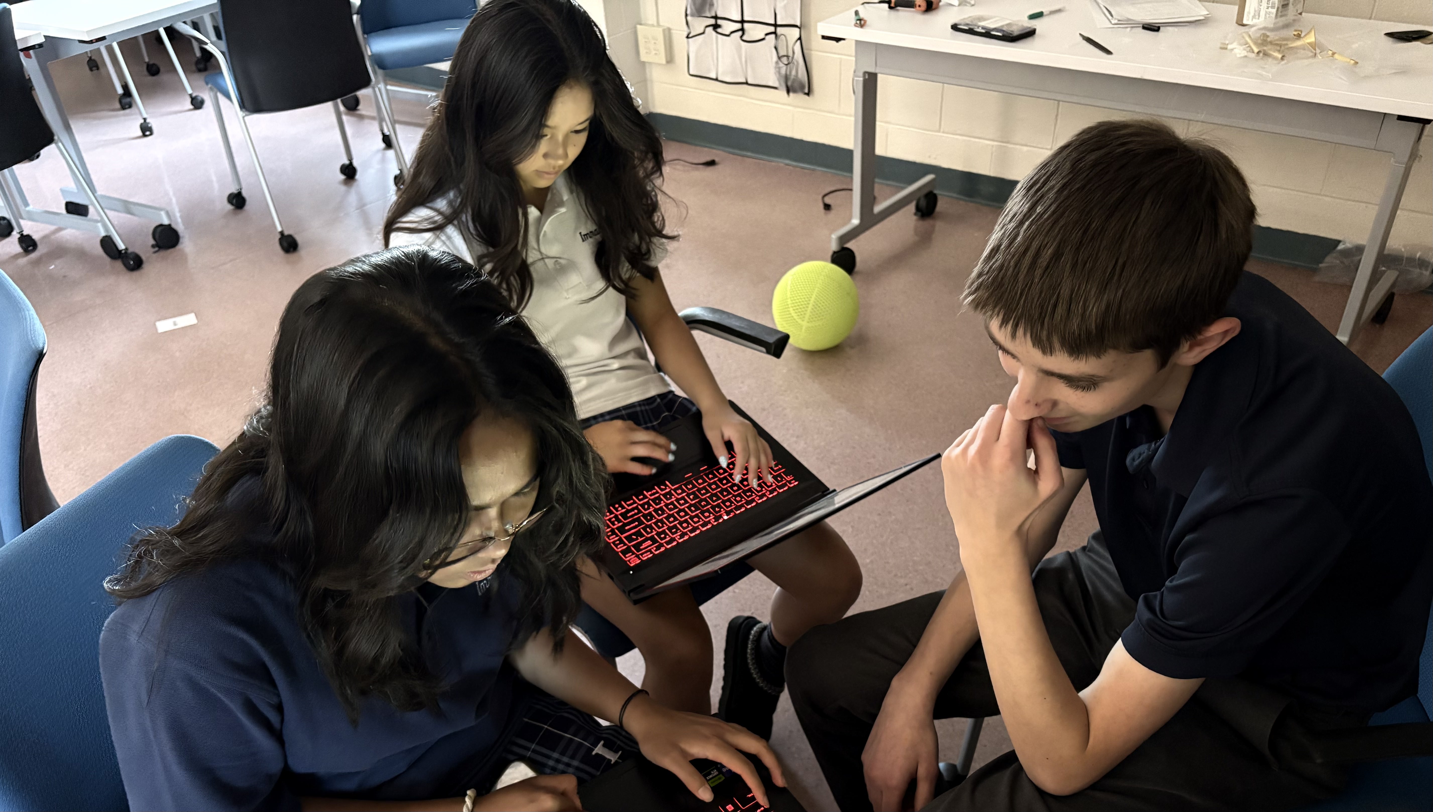 Three students working together around a laptop